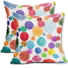 two pillows with colorful polka dot designs on them, one is white and the other is multicolored