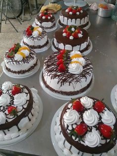 several cakes are arranged on a table with chocolate frosting and strawberries in the middle