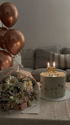 a birthday cake sitting on top of a table next to a bouquet of flowers and balloons