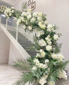 white flowers and greenery are arranged on the stairs