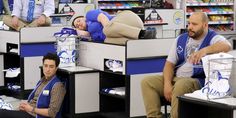 two men and a woman are sleeping on cubicles in a store with other people