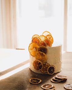 a cake with orange slices on it sitting on a table next to cookies and crackers