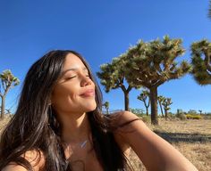 a woman sitting in the grass with her eyes closed and head tilted to the side