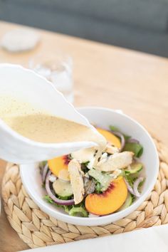 a person pouring dressing into a salad in a bowl