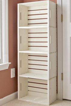 a white bookcase sitting in front of a window next to a door with pink walls