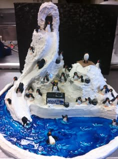 a cake with penguins on it in the shape of a mountain and ocean scene is shown