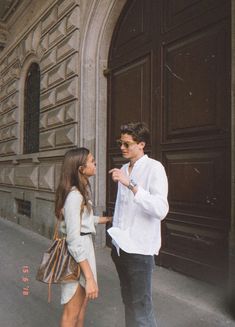 a man standing next to a woman in front of a building