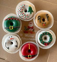 six decorated doughnuts are arranged in a circle on top of a cardboard box