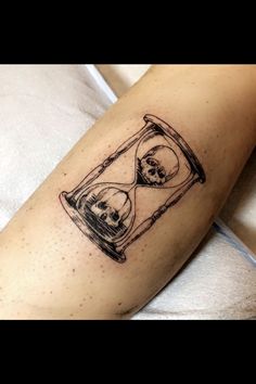 a skull in an hourglass tattoo on the leg is shown with skulls inside it