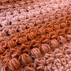 an orange and brown crocheted blanket is laying on the floor