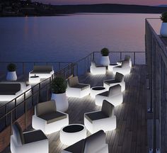 an outdoor seating area is lit up at night with lights on the tables and chairs