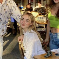 a woman sitting at a table next to a man in a white shirt and jeans