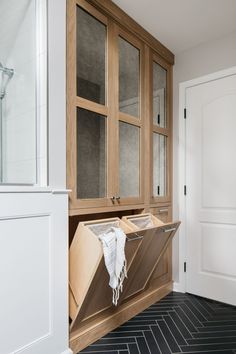 a wooden cabinet sitting in the corner of a room next to a black and white tile floor