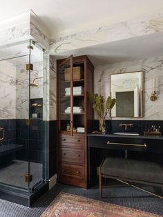 a bathroom with marble walls and flooring, black countertops, gold fixtures and a walk - in shower