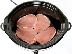 four raw meats in an electric crockpot ready to be cooked or put into the slow cooker