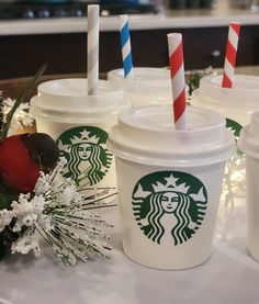 starbucks cups with straws are lined up on a table next to flowers and candles