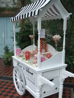 a white cart with black and white striped awning on the top that has candy in it