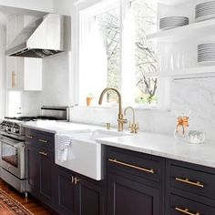 a kitchen with black cabinets, white counter tops and gold pulls on the faucet