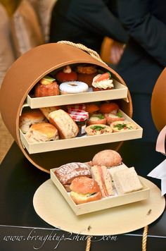 two trays filled with different types of pastries on top of a black table