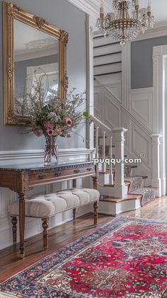 a room with a large rug, chandelier and mirror on the wall above it