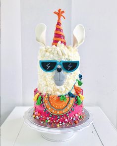 a birthday cake with a llama wearing sunglasses and a party hat on it's head