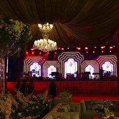 a stage set up for a wedding with flowers and chandeliers on the ceiling