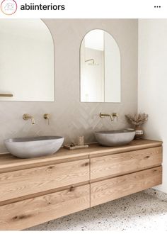 there are two sinks in the bathroom with mirrors on the wall above them and an oval mirror