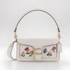 This beautiful Coach Tabby shoulder bag is a must-have for any fashion-forward woman. The bag is made of high-quality leather with a chalk exterior color and features a stunning floral pattern with embroidered accents. The bag has a medium size, measuring 10 1/2 inches in width, 6 inches in height, and 3 inches in depth. The bag has a magnetic and snap closure and an adjustable leather strap that can be worn over the shoulder or across the body. The interior lining is made of soft suede and features a bag charm. The Coach Tabby model is a classic and timeless piece that belongs in every woman's collection. Coach Tabby Shoulder Bag, Tabby Shoulder Bag 26, Coach Mini Bag, Style 2025, Tabby Shoulder Bag, Shoulder Purses, Coach Tabby, 2025 Mood, Baggage Claim