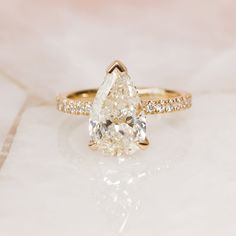 a pear shaped diamond engagement ring with pave diamonds