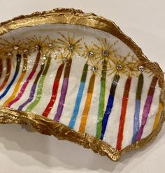 a gold plate with multicolored candles on it