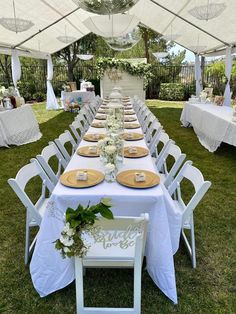 a long table set up with plates and place settings for an outdoor wedding reception in the grass