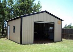 a garage with the door open in front of some trees and grass on either side