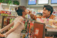 a man and woman in a grocery store talking to each other while the girl is touching her nose