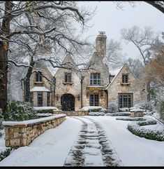 a stone house is covered in snow and surrounded by trees, shrubs and shrubbery