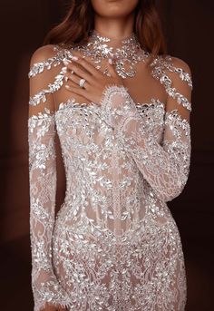 a woman in a white dress with long sleeves and flowers on her body is posing for the camera