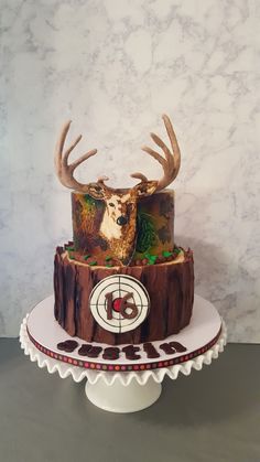 a cake decorated with deer's head on top of a wooden table next to a marble wall