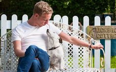 a man is sitting on a bench with his dog and petting it's nose