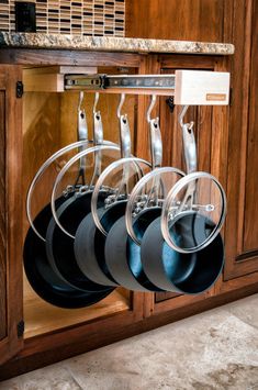 pots and pans are hanging from the wall in this kitchen cabinet with wooden cabinets