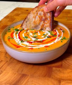 a person dipping some bread into a bowl of soup