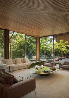 a living room filled with lots of furniture and large windows overlooking the trees in the background