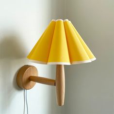 a lamp that is on the wall next to a light fixture with a yellow shade