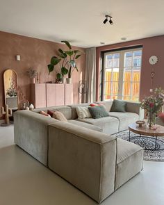 a living room filled with furniture and a large window covered in pink curtains next to a white floor