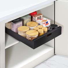 an open drawer in a kitchen filled with spices and other food items on the shelves