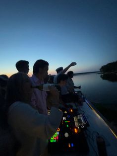 a group of people sitting on top of a boat at night with the sun setting