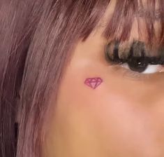 a woman's face with a pink diamond tattoo on her left side of the eye