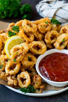 the plate is full of fried shrimp and ketchup with lemon wedges on the side