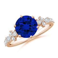 an oval blue sapphire and diamond ring with two side stones on the band, set in 18k rose gold