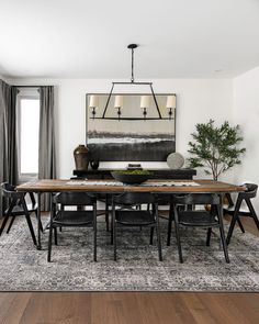 the dining room table is surrounded by black chairs and an area rug that matches the hardwood flooring