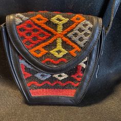 This Handmade Bag Is Beautifully Crafted With Blank Leather And 100% Dyed Wool Kilim From Turkey. This Bag Was Never Used, Safely Stored With The Original Tags And Information. It Has A Magnetic Closure, Adjustable 50 Inch Strap With Brass Hardware, Original Had Tag, And Information Tag With Price. The Kilim Has A Black Background With A Red, Brown, Orange, Gray, And Green One Of A Kind Design. You Will Not See This Bag Coming And Going. Unique And Stunning! Retro Black Crossbody Shoulder Bag, Vintage Black Bag With Adjustable Strap, Traditional Black Bag For Everyday Use, Traditional Black Rectangular Shoulder Bag, Vintage Black Shoulder Bag With Snap Closure, Traditional Black Tote Shoulder Bag, Traditional Black Satchel For Everyday Use, Vintage Black Pouch Shoulder Bag, Black Vintage Bag With Snap Closure