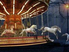 three white horses are on a carousel at night